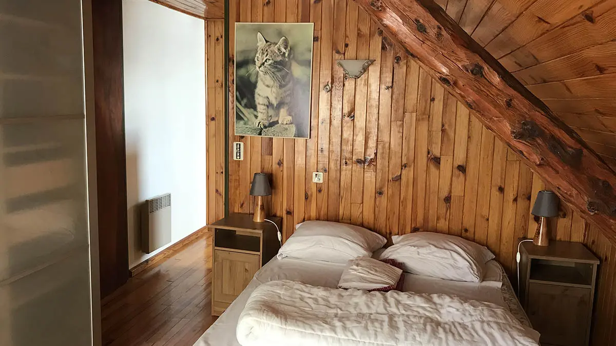 Attic bedroom with double bed, wooden furniture, parquet flooring