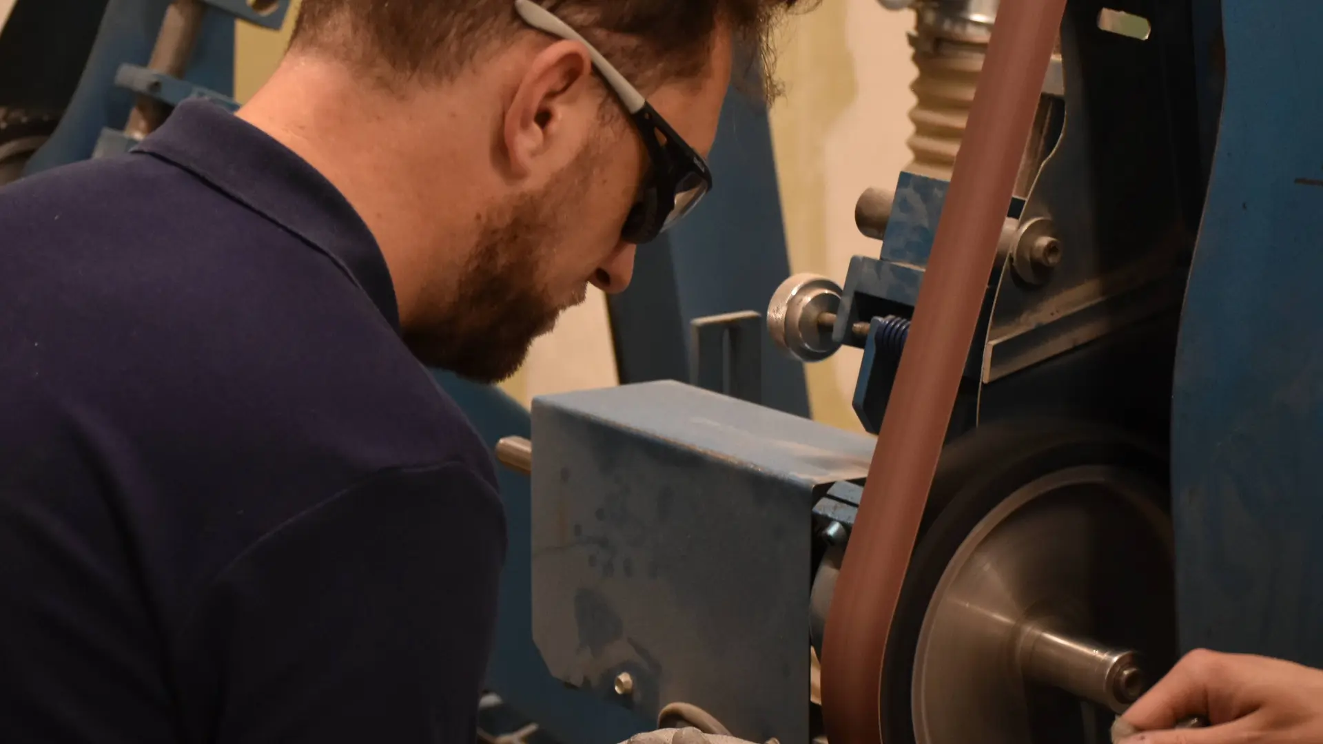 On voit la manière dont le coutelier meule le manche en bois du couteau