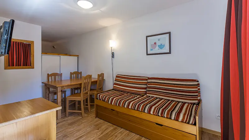 Séjour d'appartement avec canapé-lit, table à manger, TV murale