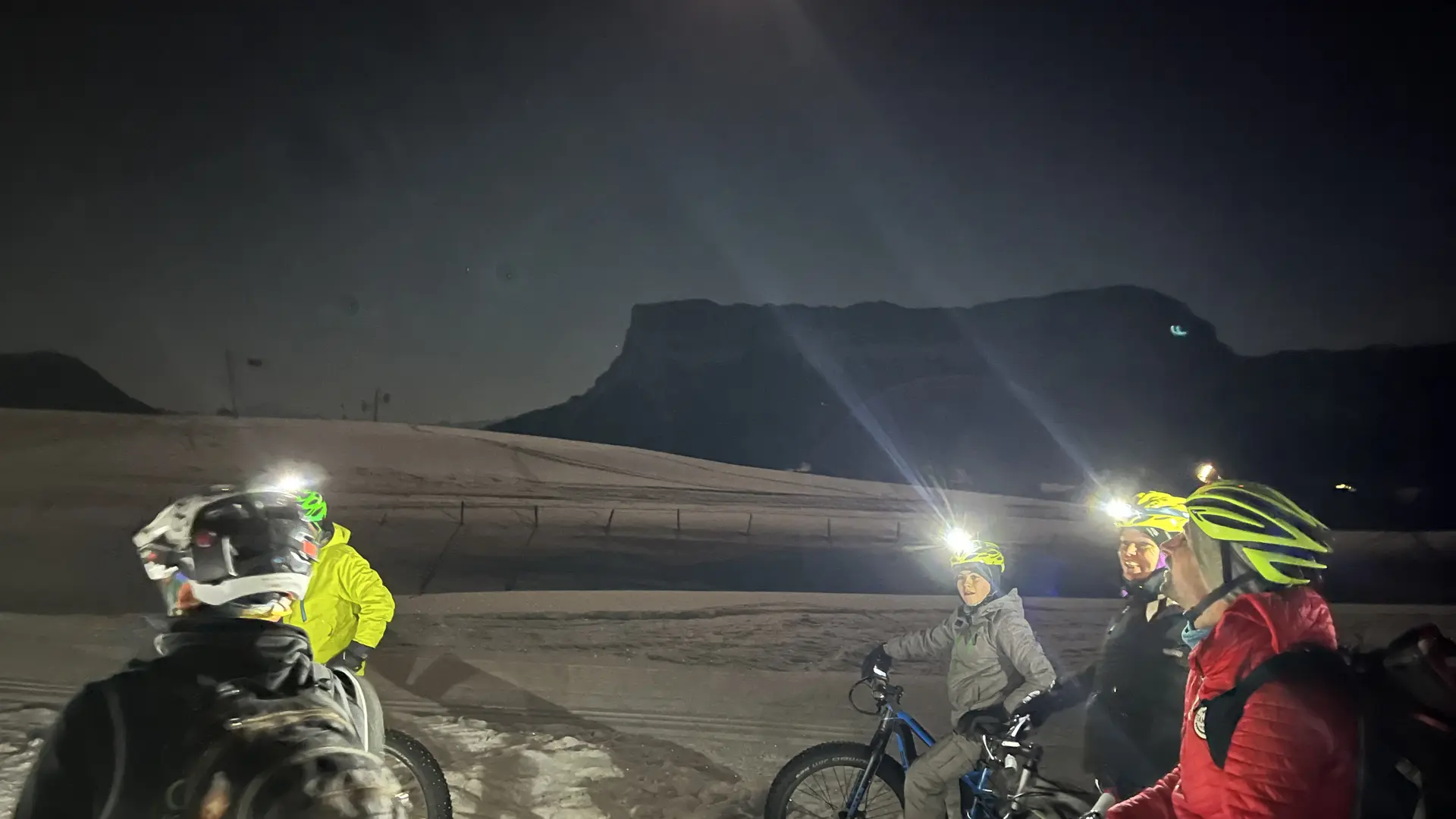 Sortie nocturne Fatbike sur la neige. Les cyclistes ont tous des lampes frontales.
