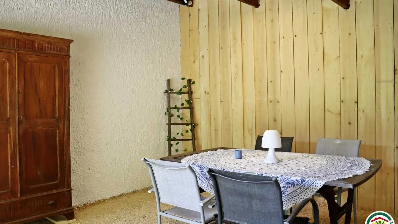 Terrasse couverte d'extérieur avec table, bains de soleil et plancha à disposition.