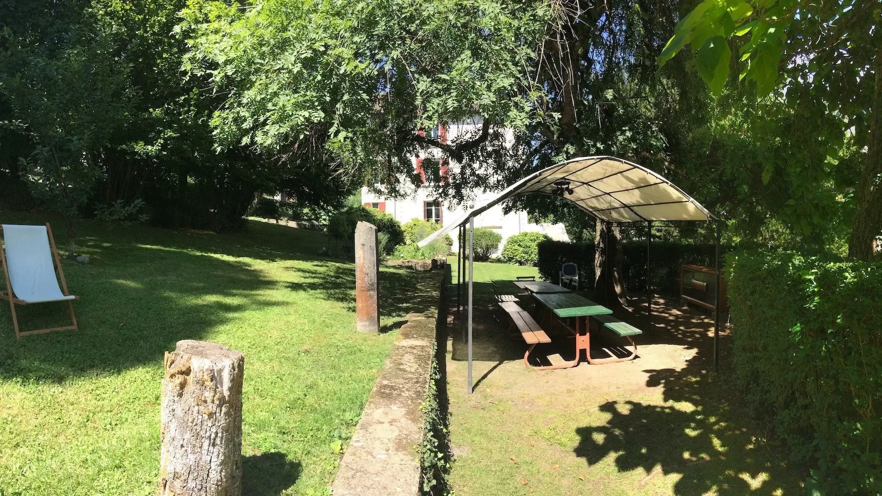 Le jardin de la résidence de l'Europe offre un espace de détente en plein air, avec une table de pique-nique et une chaise longue installés sous un abri.