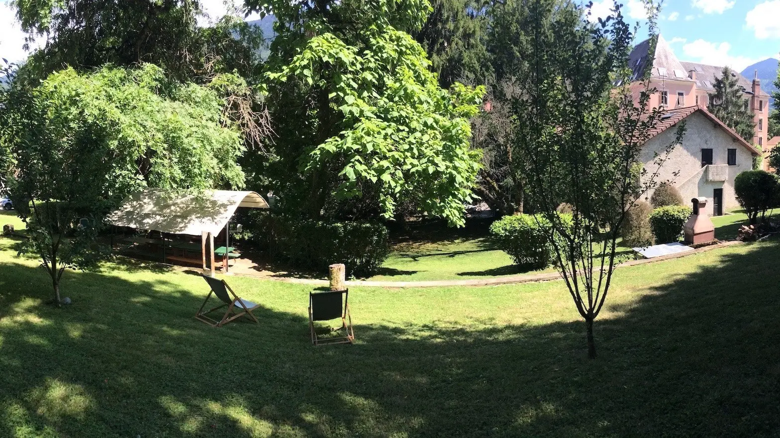 Le jardin verdoyant de la résidence de l'Europe, agrémenté d'une table de pique-nique ombragée et de chaises longues.