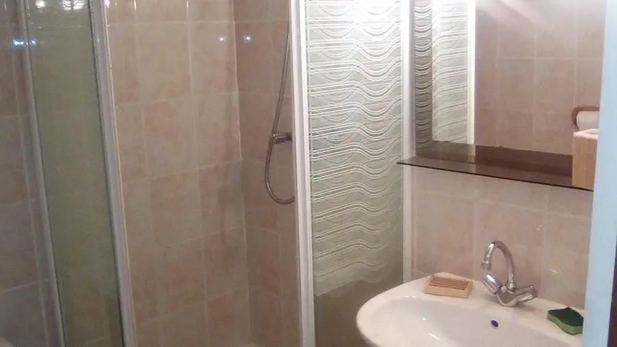 Salle de bains carrelée avec bac de douche et évier