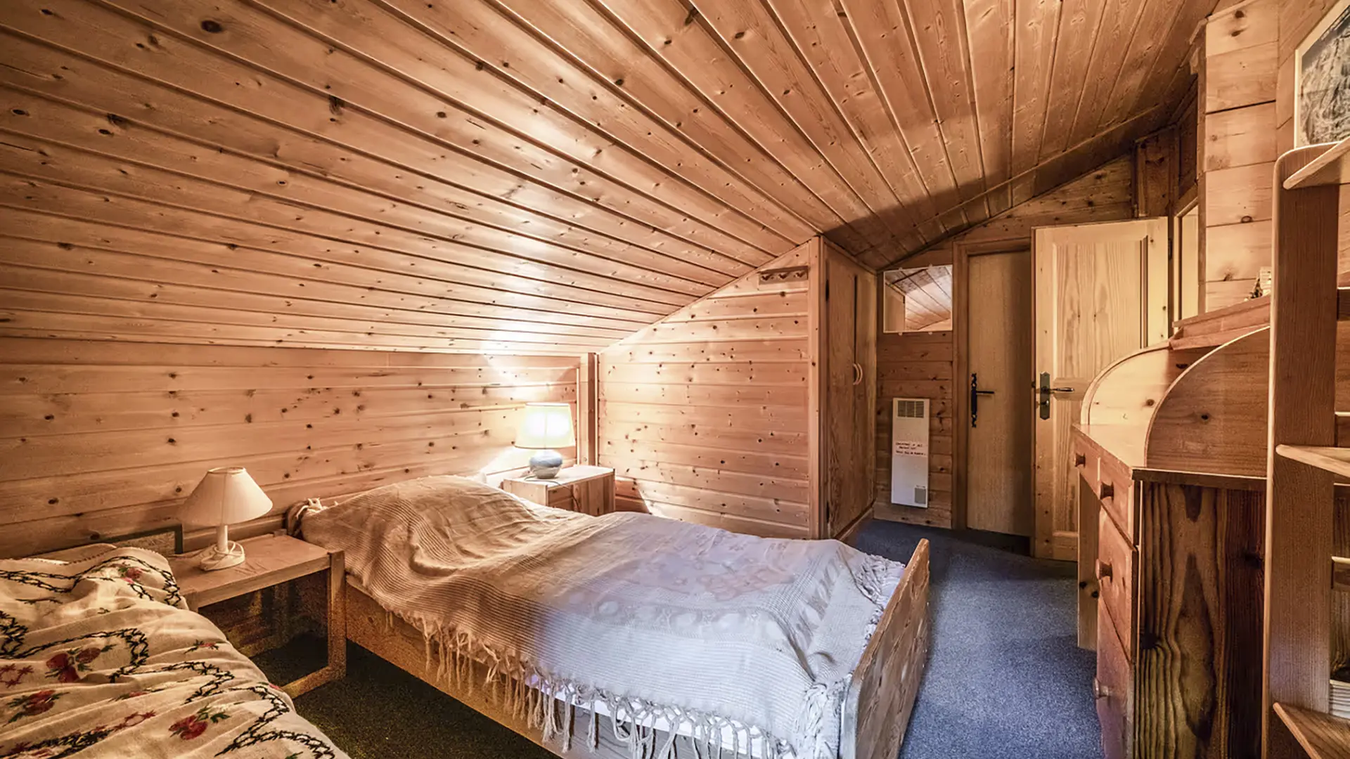 Chambre mansardée avec lit simple, banquette, commode