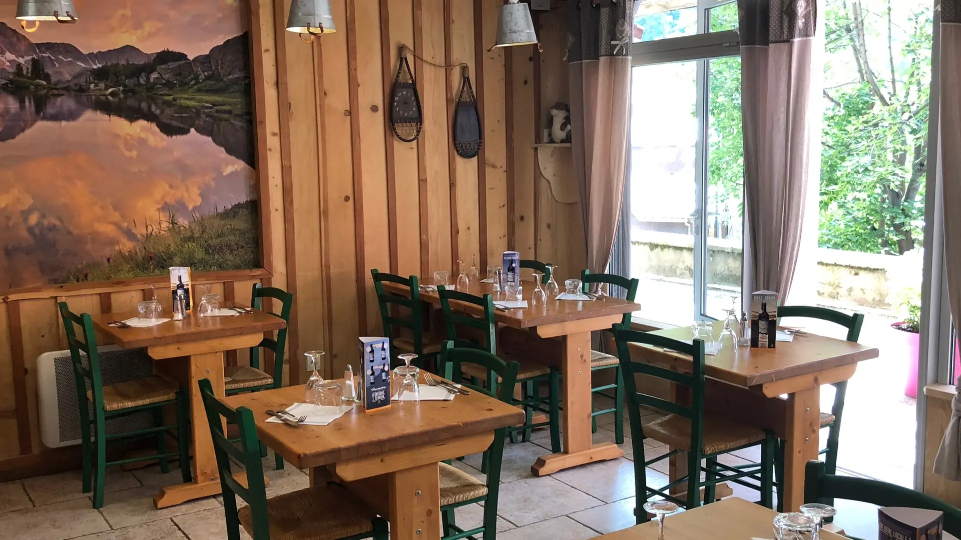 Bright restaurant dining room with wooden interior decor, matching tables and chairs, painting on the wall, French doors opening onto the shopping arcade