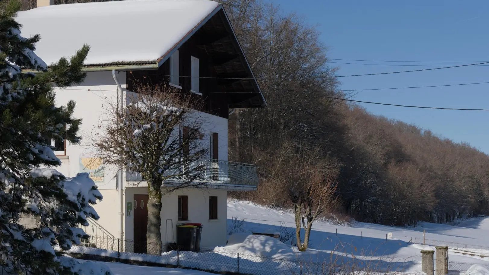 Le gite sous la neige avec vue sur le pré et la forêt