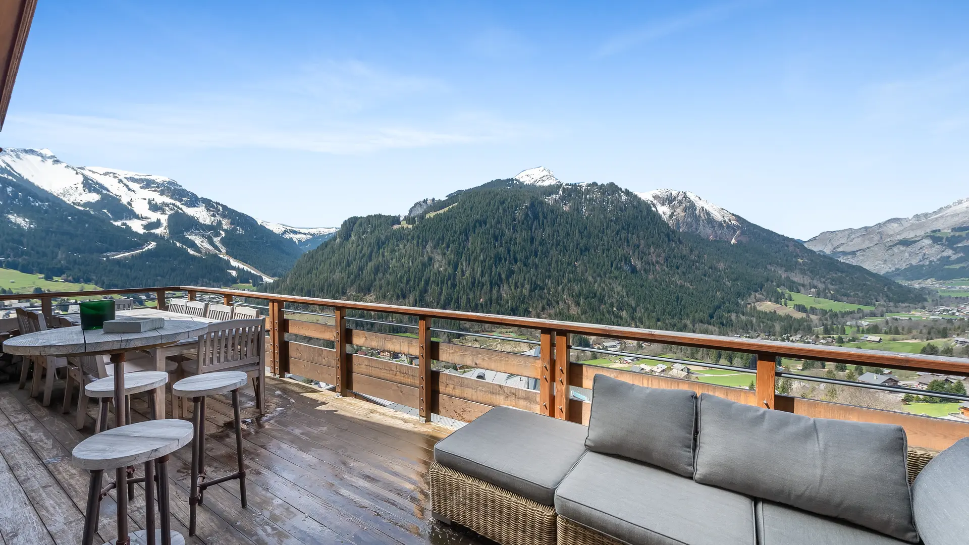 Grande terrasse avec canapé, grande table, vue panoramique sur le village et les montagnes