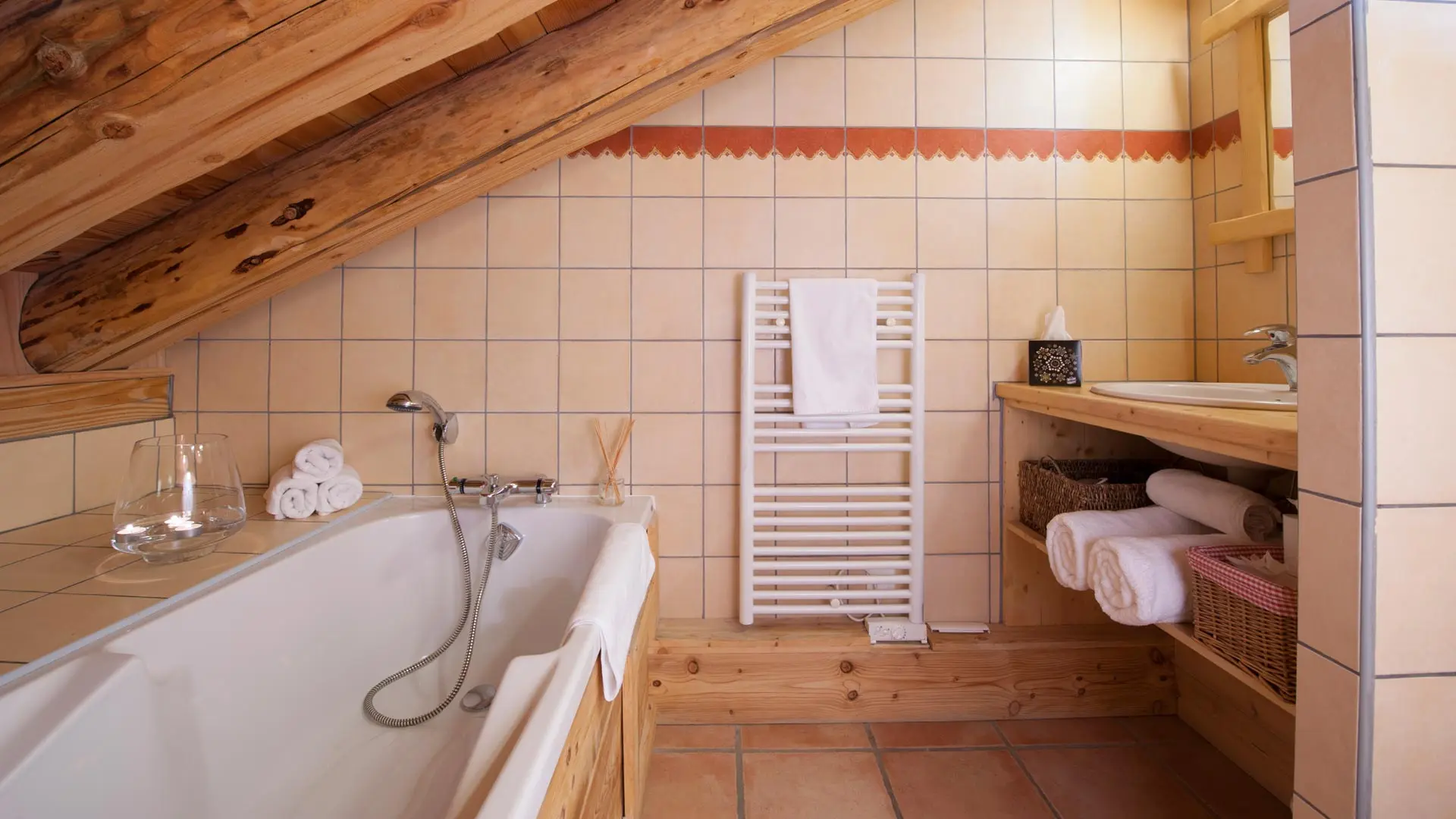 Salle de bain mansardée, sèche serviette, vasque, miroir, rangements.