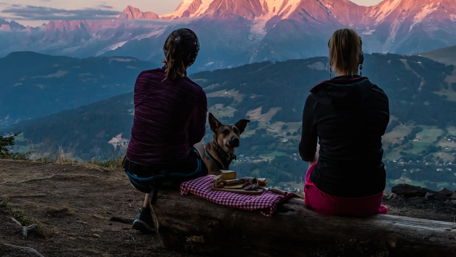 Deux randonneuses en train de pique-niquer face aux montagnes au coucher du soleil