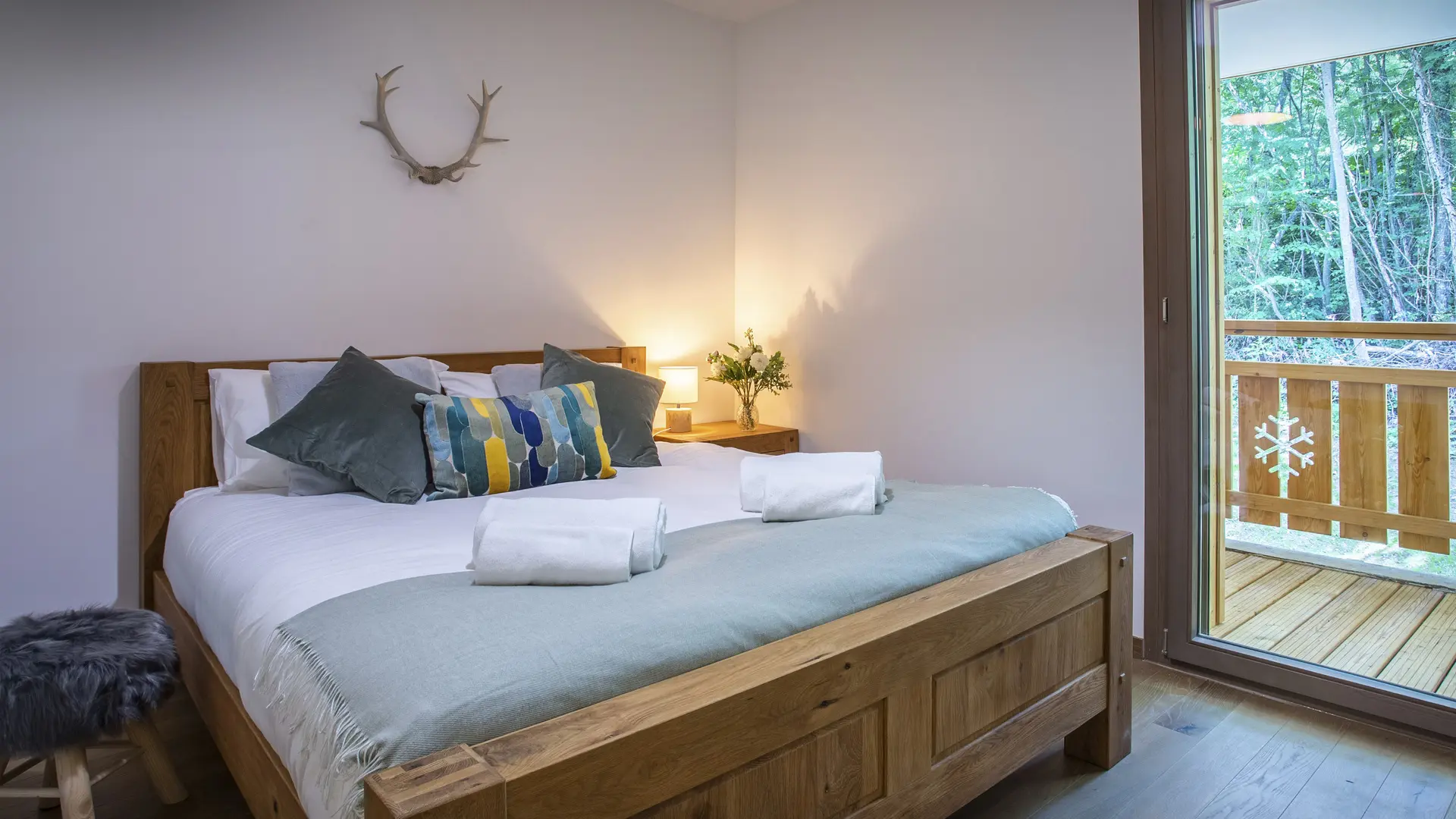 Chambre double avec son grand lit une porte fenêtre donnant accès au balcon et vue sur les montagnes