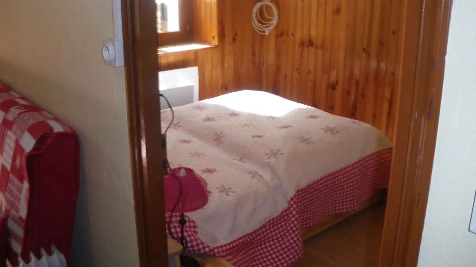 Chambre à coucher lumineuse avec lit double, ameublement bois, parquet au sol, fenêtre