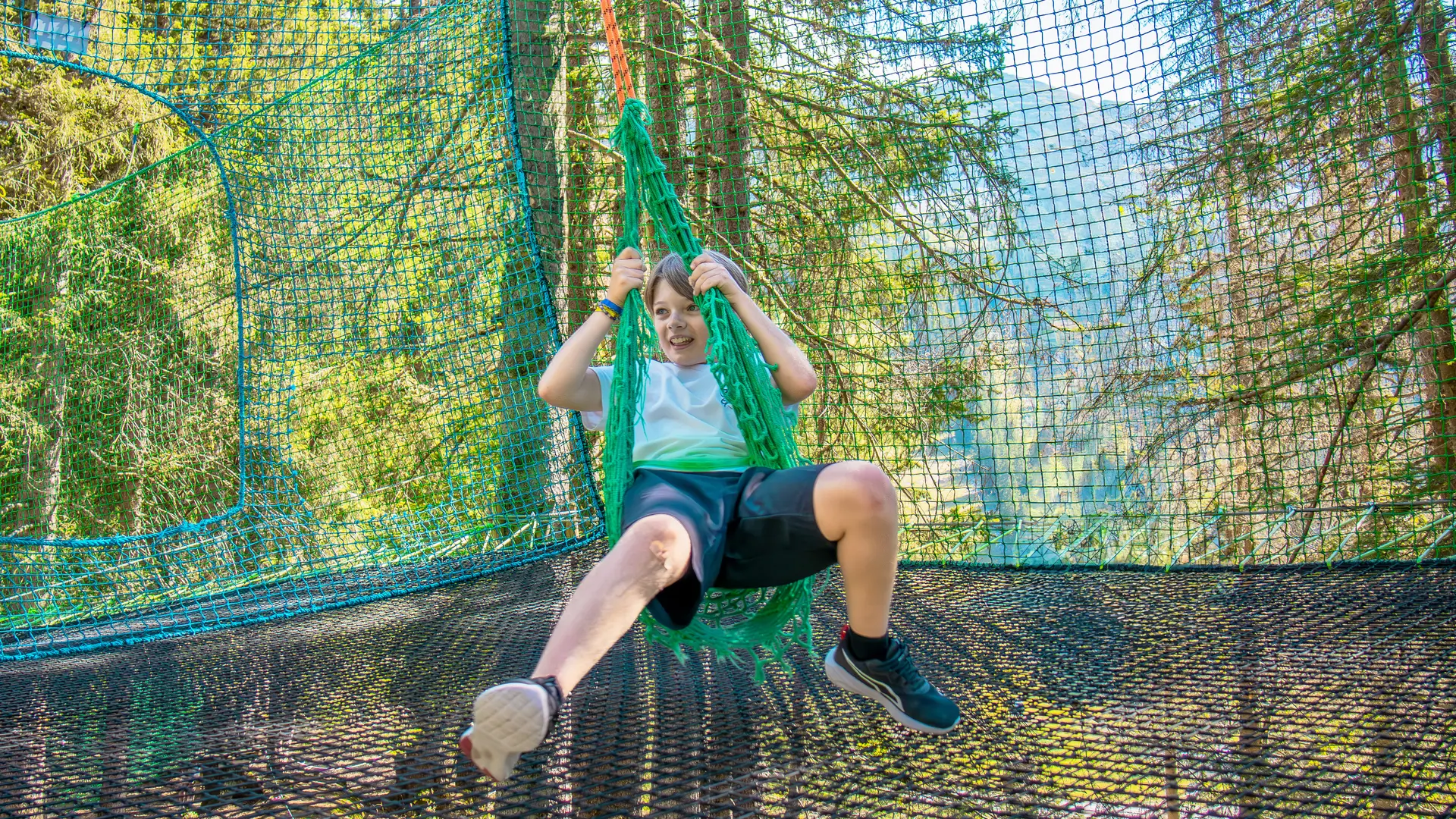 Un enfant assis sur la balançoire de l'accro-fun