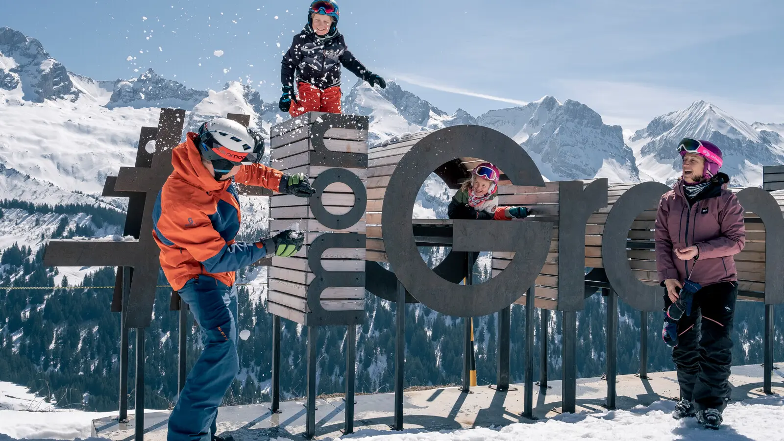 Famille de skieurs sur le domaine de ski alpin du Grand-Bornand, se lançant des boules de neiges face à la chaîne des Aravis