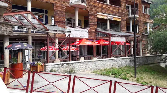 View of the restaurant from outside the shopping mall. Outdoor terrace with parasol. Sign with the inscription: Pourquoi pas, cheese specialties