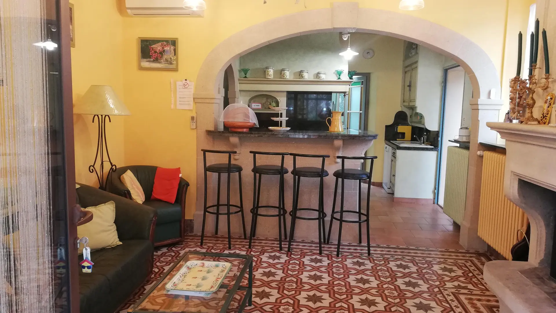 Un salon convivial avec bar et cheminée, sublimé par des carreaux anciens et une décoration chaleureuse.