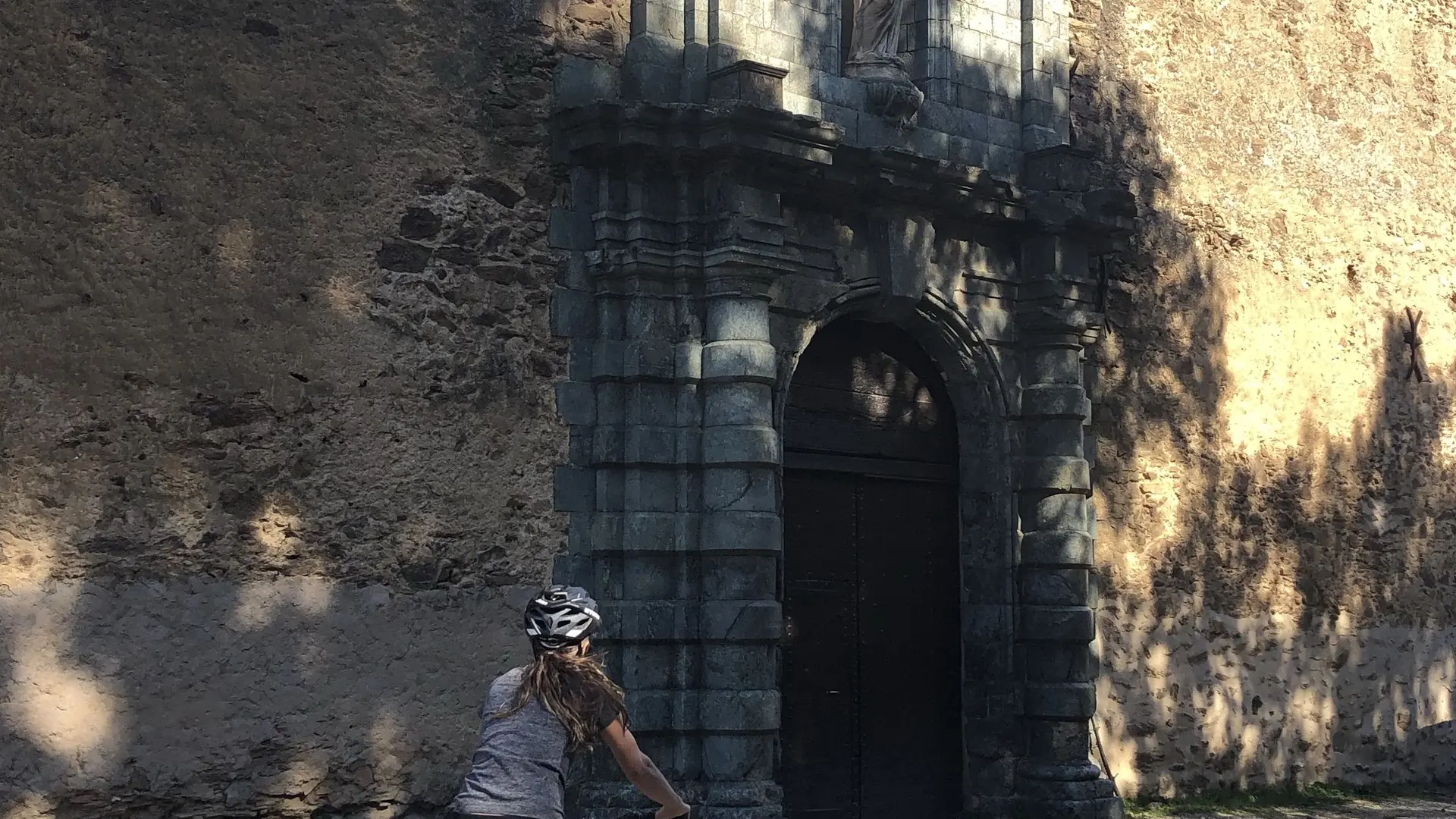 Cycliste devant l'imposante porte de la Chartreuse de la Verne