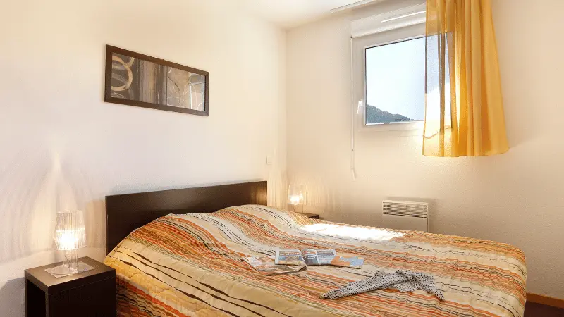 Apartment bedroom with double bed, porthole window, French doors opening onto a balcony