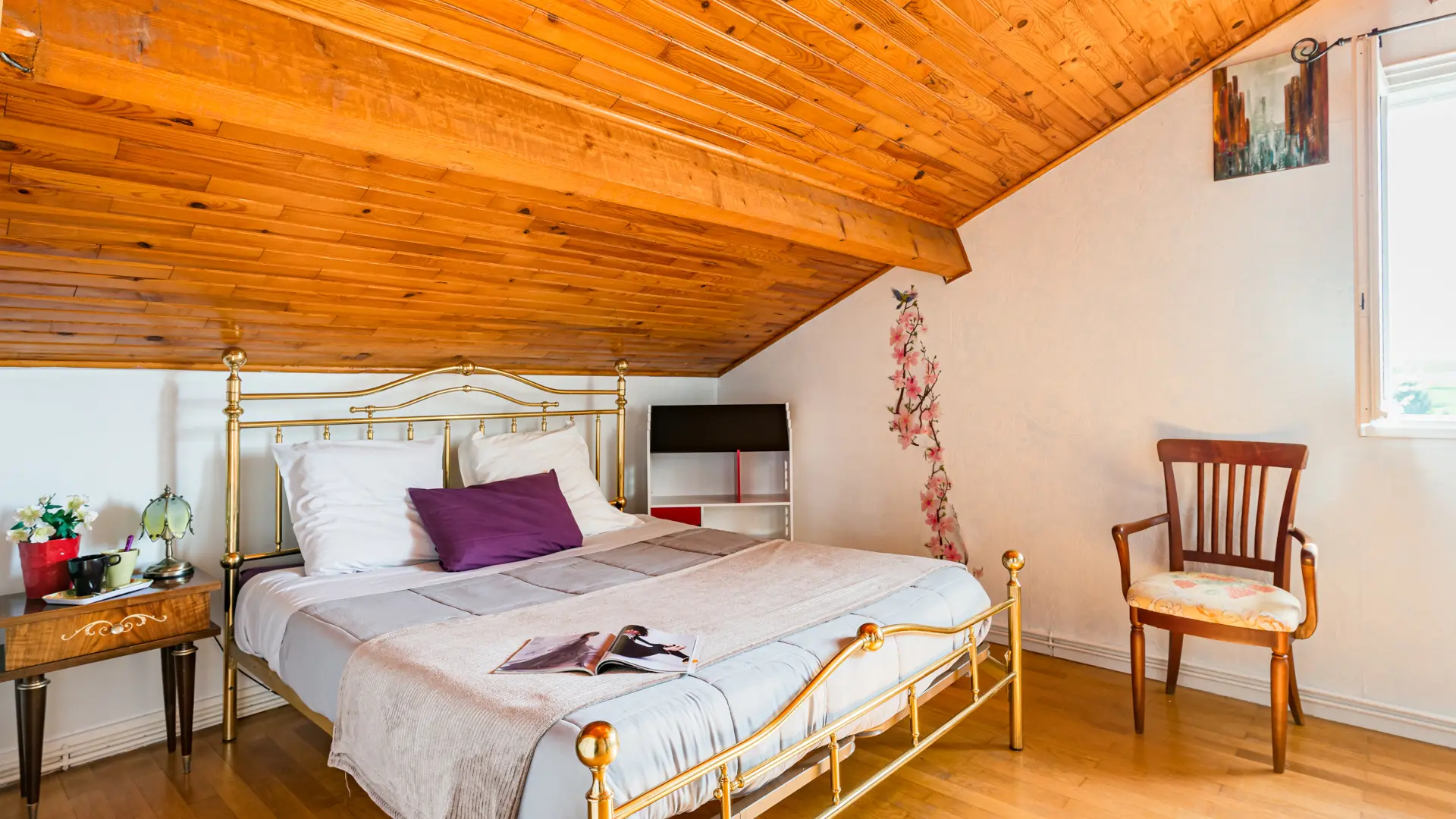 Chambre Iris de la Suite Perle : lit en laiton et plafond en bois, ambiance chaleureuse et cosy