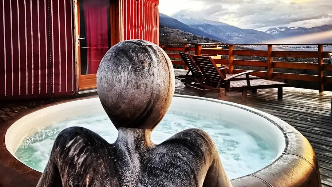 Sculpture en bois représentant un homme accroupi devant le jacuzzi de la terrasse.