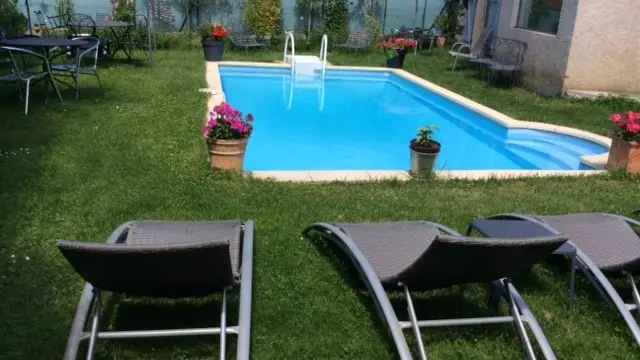 Un espace extérieur aménagé avec une piscine, une pelouse, quelques transats.
