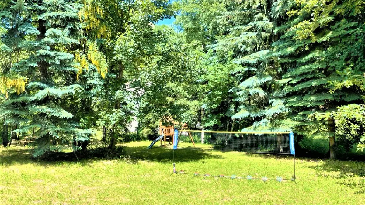 Jardin ensoleillé avec aire de jeux et filet de volley-ball