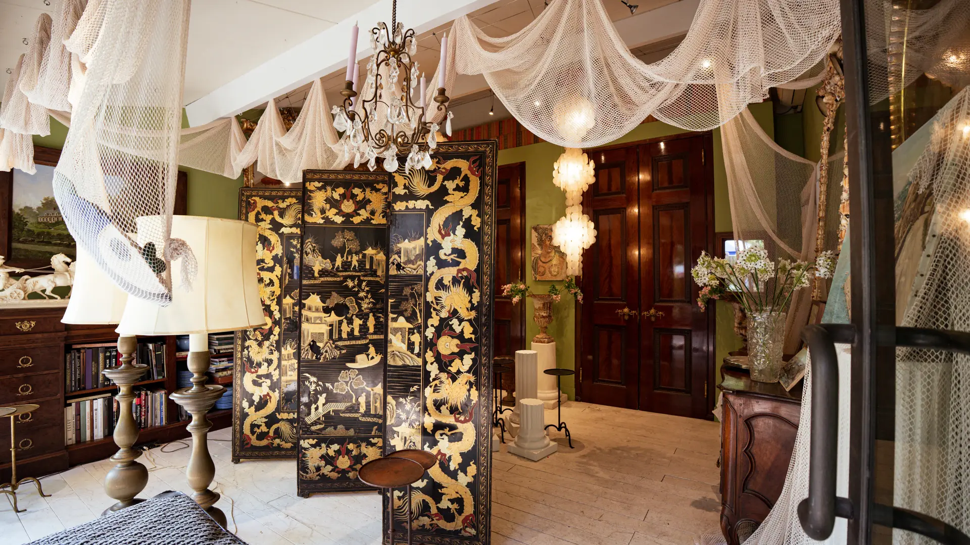 Un paravent asiatique, des filets suspendus et des objets anciens créent une ambiance théâtrale et immersive.