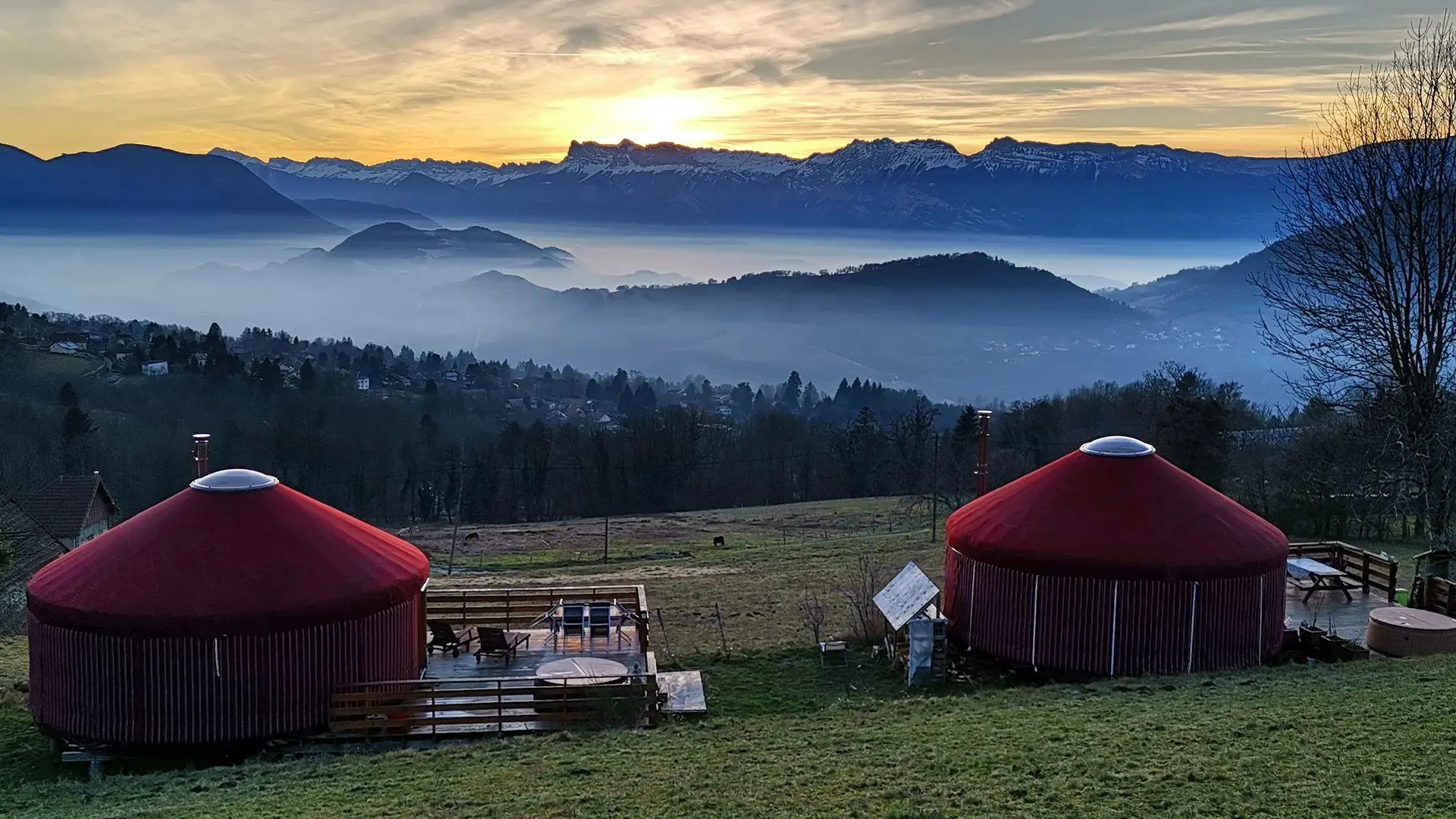 Deux yourtes rouges avec leurs terrasses au soleil couchant avec le Vercors au fond.