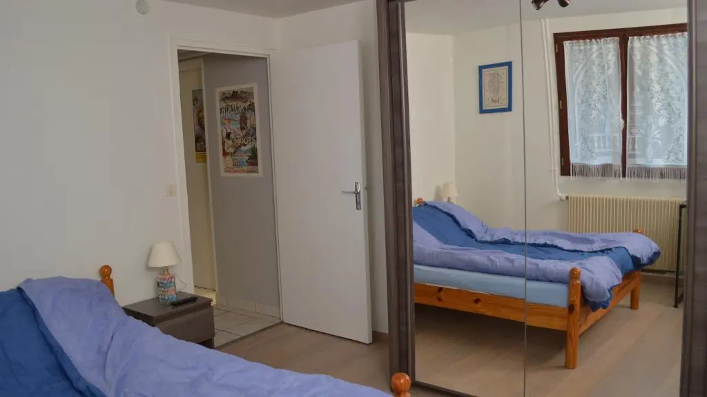 Chambre avec lit double, non décorée, et grande penderie avec grand miroir donnant sur le lit