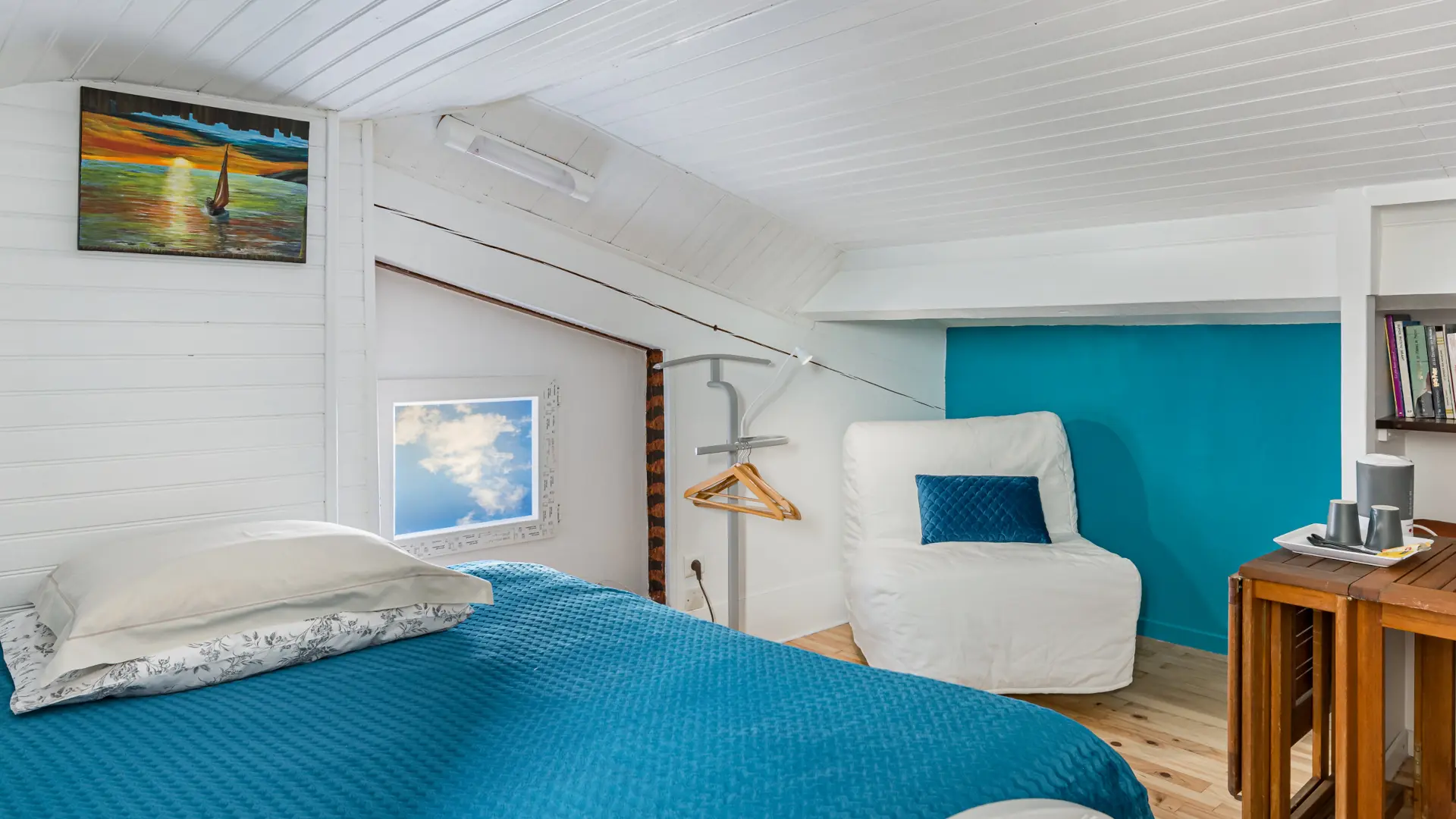 Chambre Goélette : vue 3/4 du lit principal, canapé-lit enfant en fauteuil de repos, coin détente