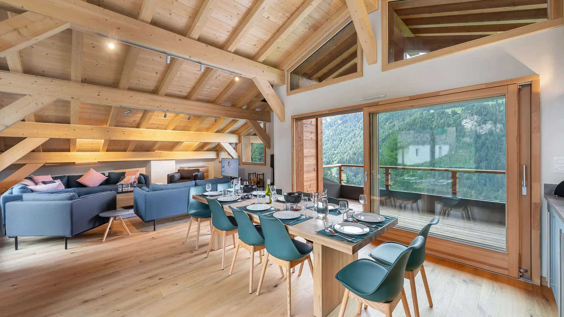 Vue du séjour avec espace salle à manger, coin salon, poutres apparentes et grandes baies vitrées