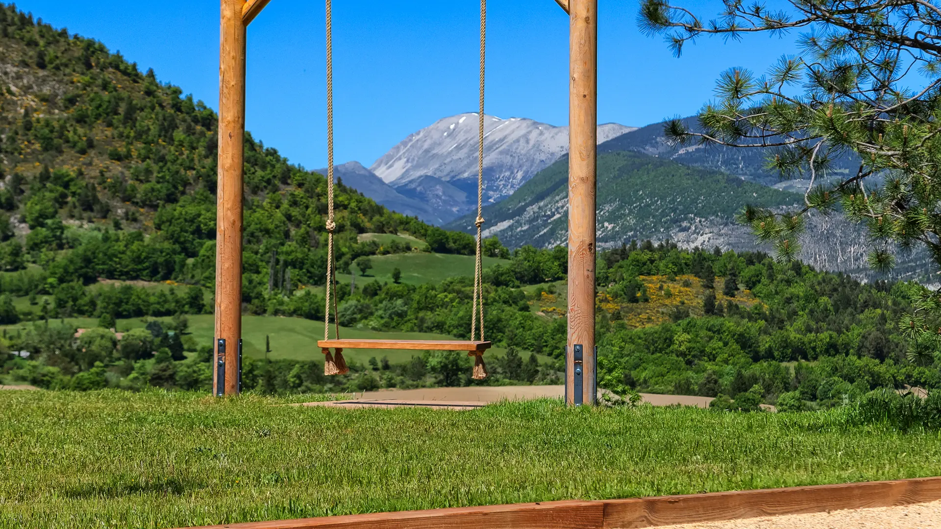 Balançoire suspendue avec vue panoramique sur la vallée et terrain de pétanque