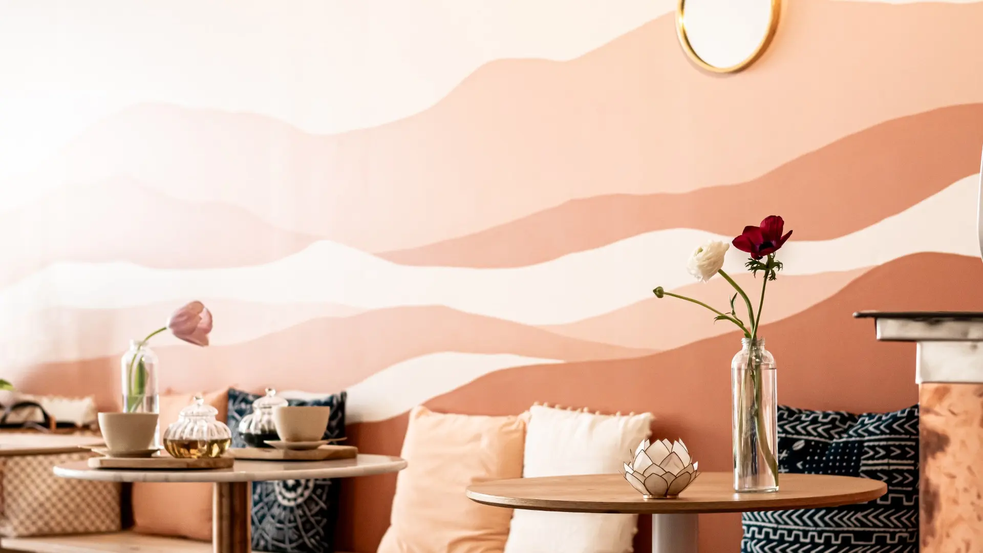 Petites tables rondes, banc et coussins disposés à l'intérieur du café.