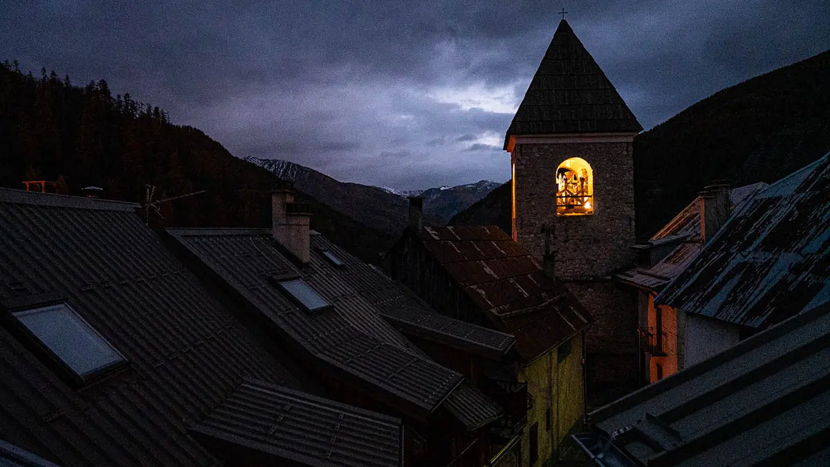 View from the flat, roofs of the village, bell tower and snow-capped mountains in the distance