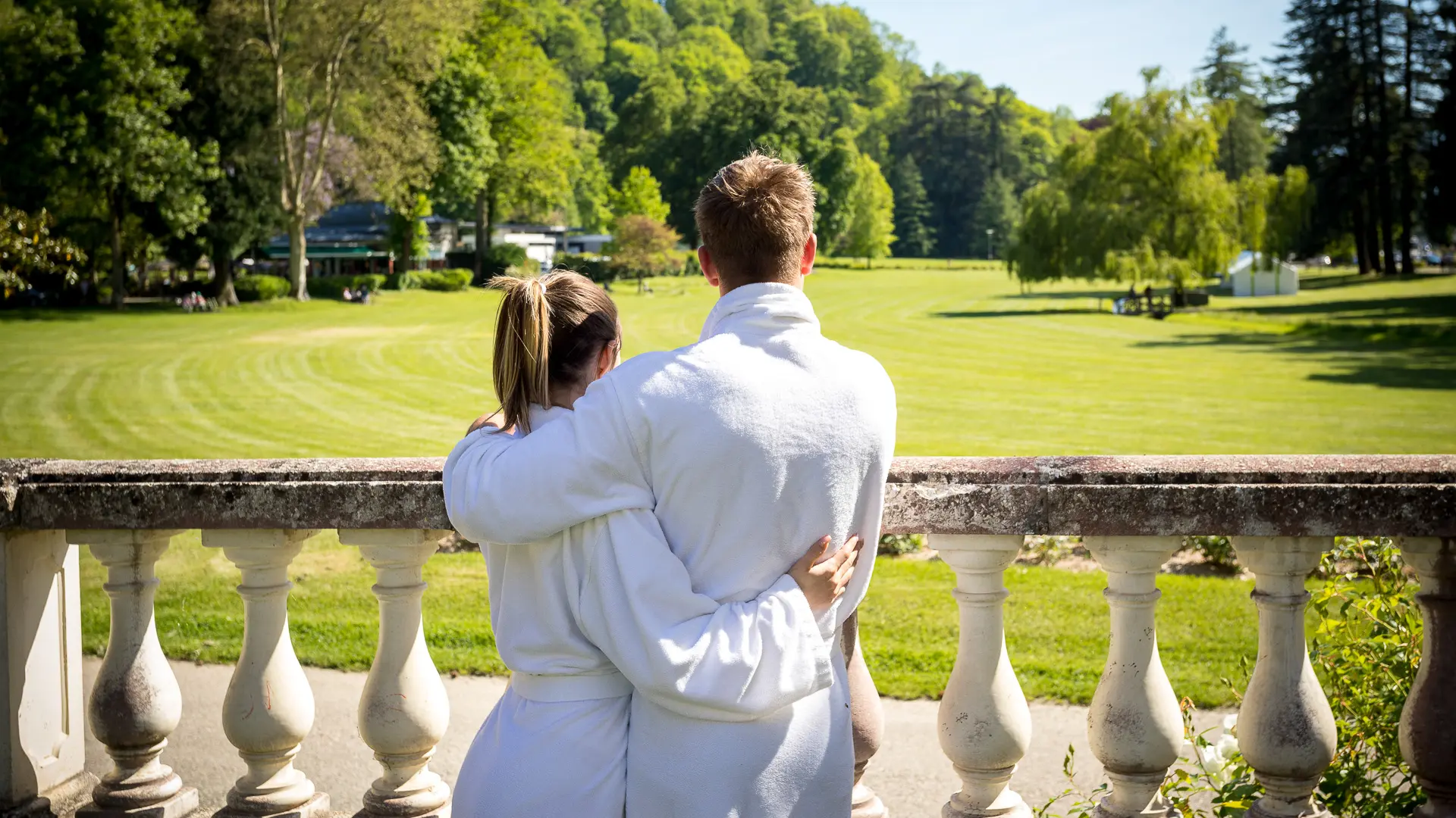 Un couple de dos en peignoir admirent le parc thermal.