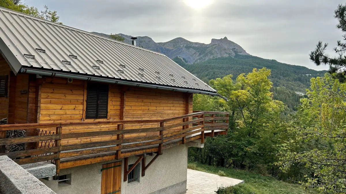 View of the two-storey stone and wood cottage with terrace and garden