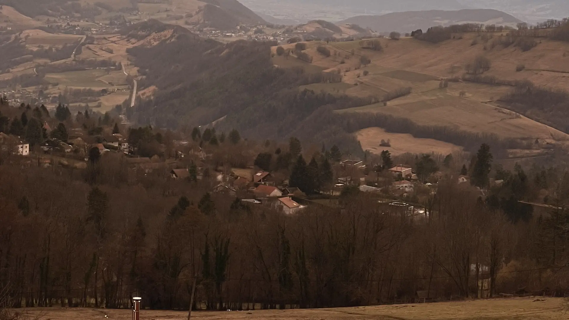 La photo représente une vaste étendue de terrain herbeux avec à l'horizon une chaîne de montagnes dont les sommets sont baignés dans la lumière d'un coucher de soleil. Au premier plan, on distingue deux yourtes traditionnelles, l'une de couleur rouge, posées sur le sol.