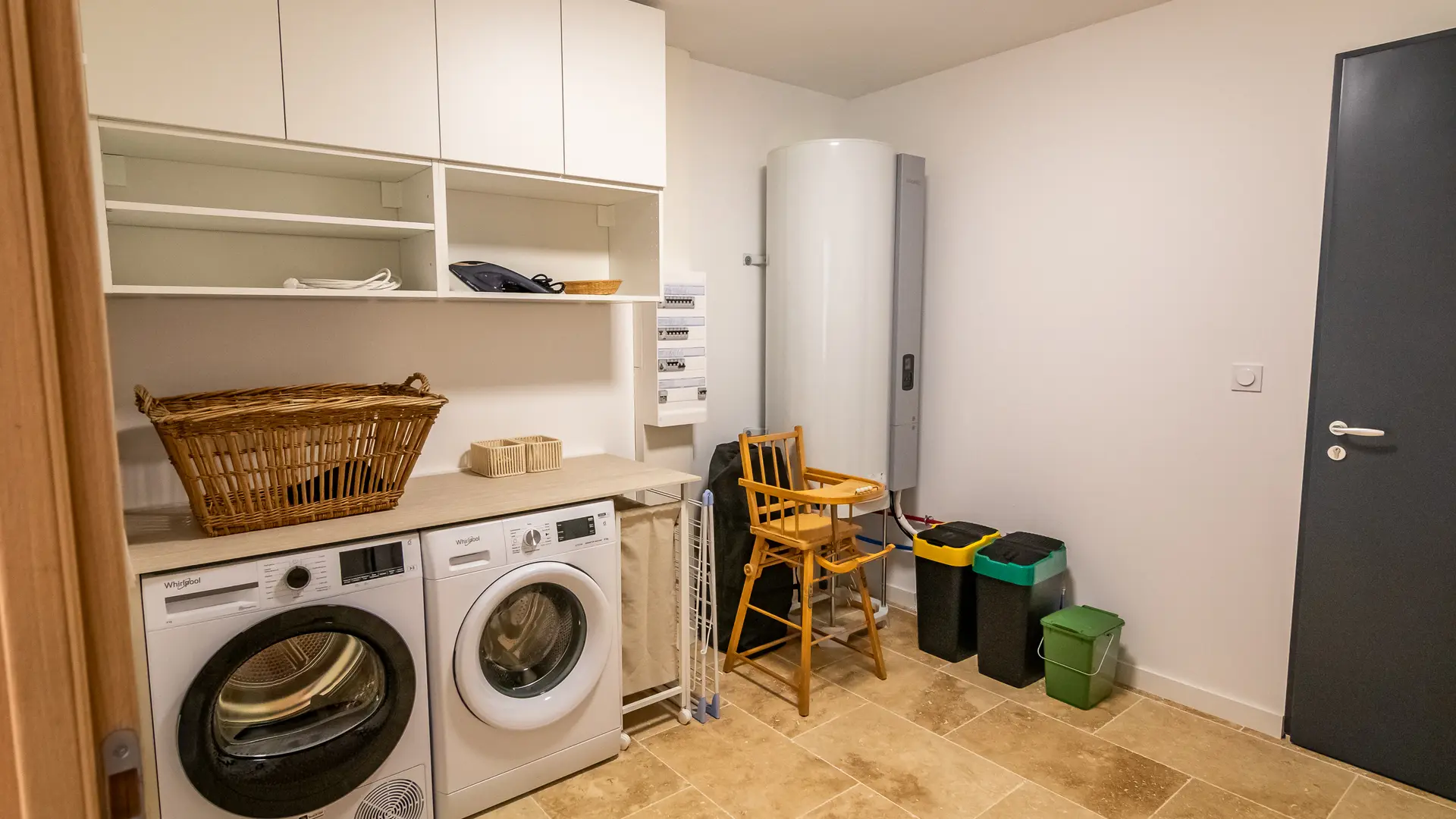 Espace buanderie avec machines, tri sélectif et équipements bébé