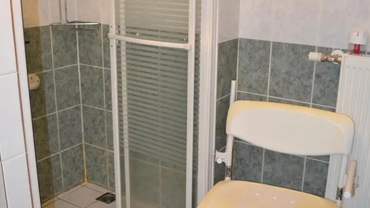 Salle de bains et fauteuil avec accoudoirs amovibles.