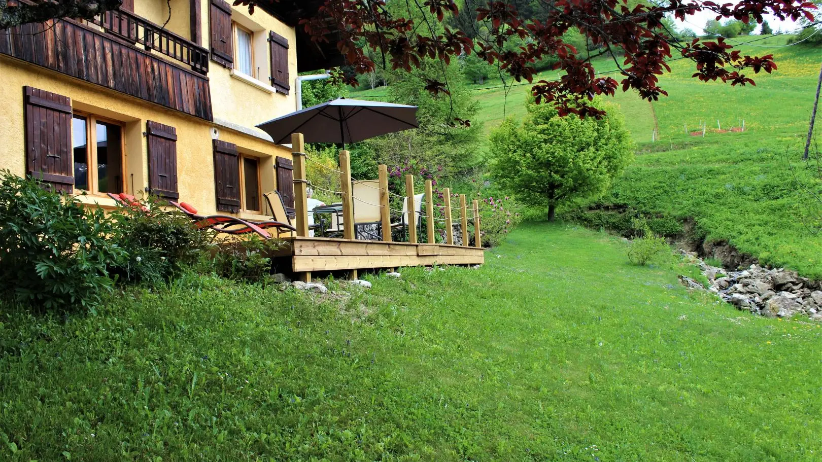 Terrasse et terrain avec ruisseau devant le gîte