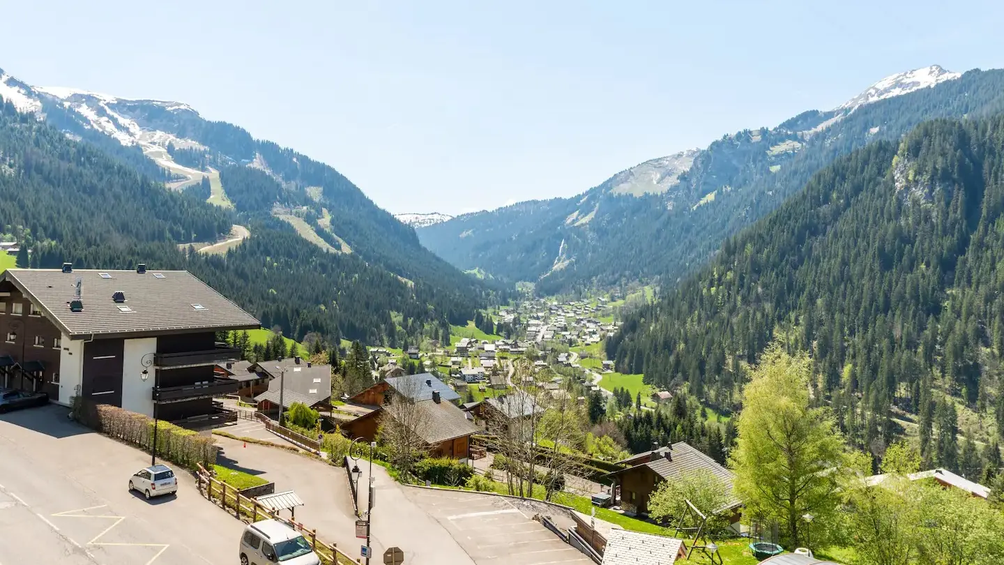 Vue depuis l'appartement sur les montagnes et le village, parking au pied de la résidence