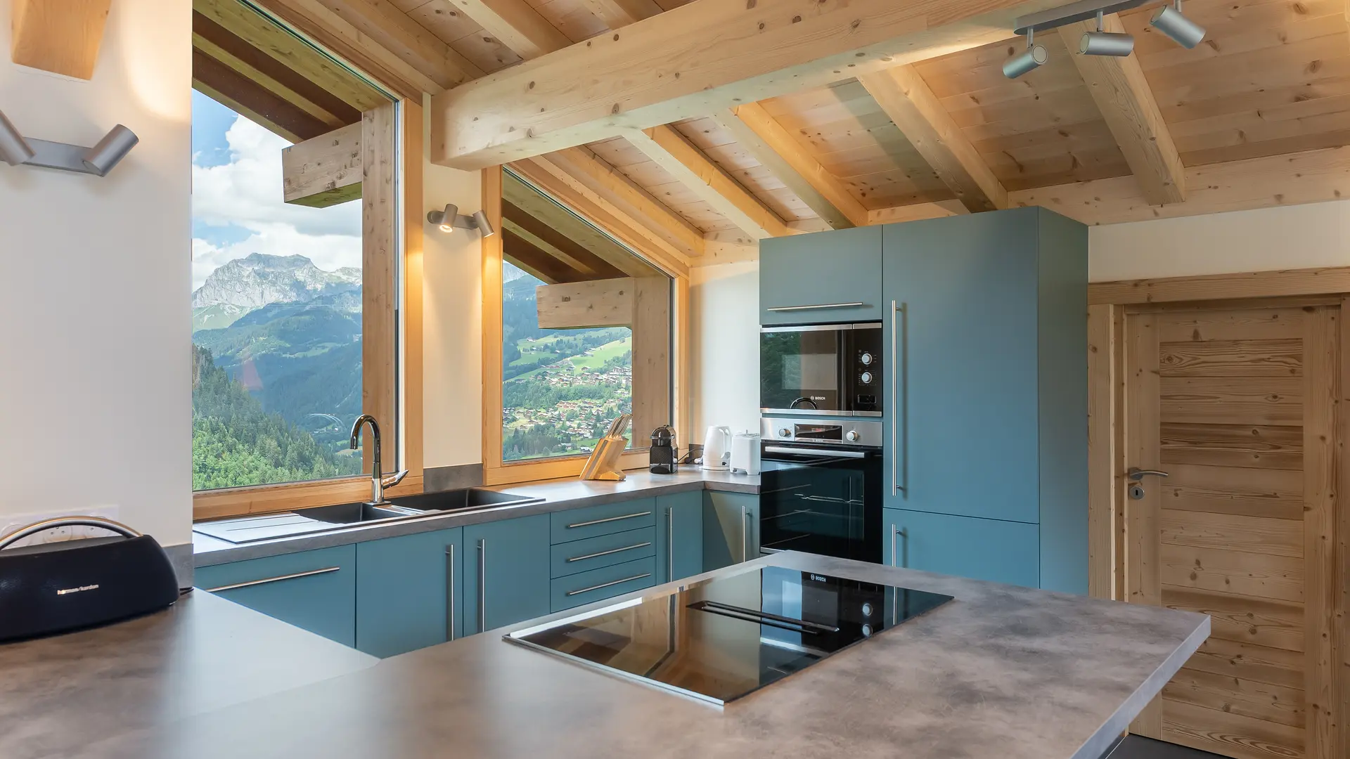 Cuisine moderne toute équipée, meubles bleus, grand ilot, fenêtres