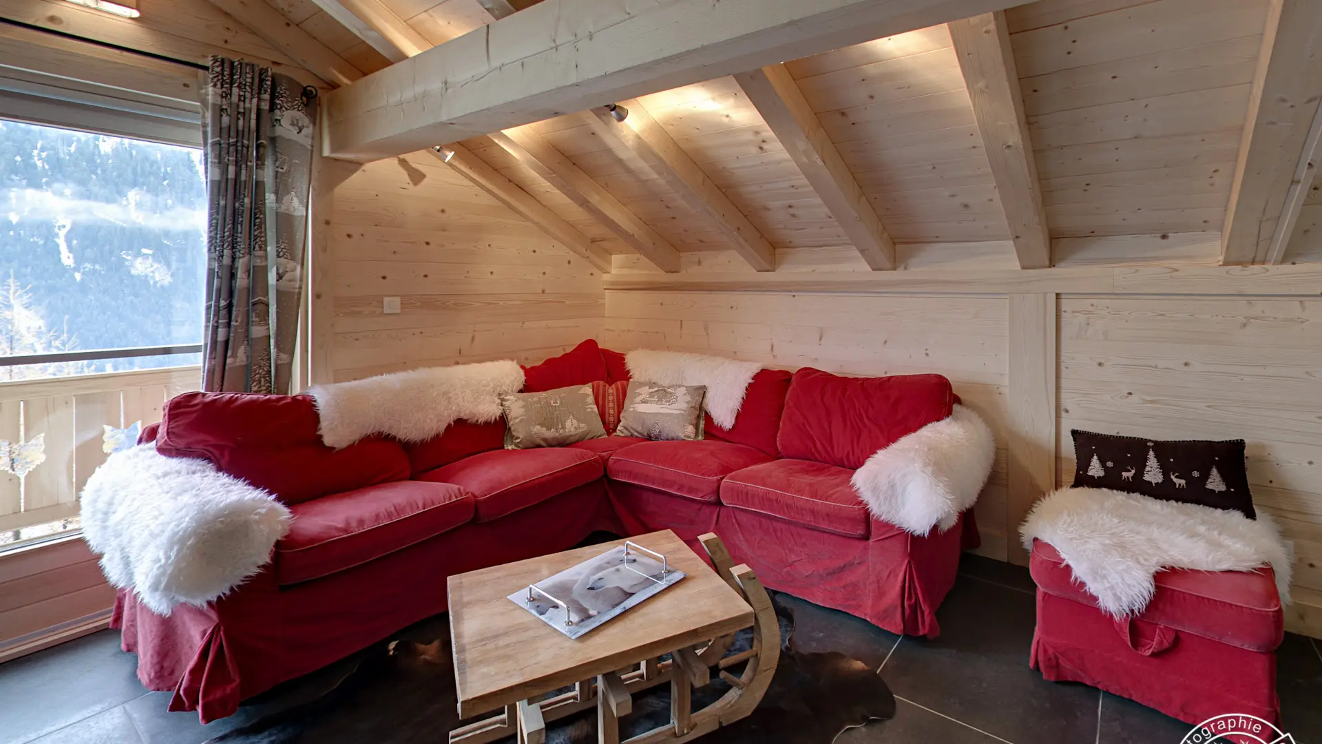 Espace détente avec canapé et fauteuil, table basse, porte fenêtre donnant accès au balcon