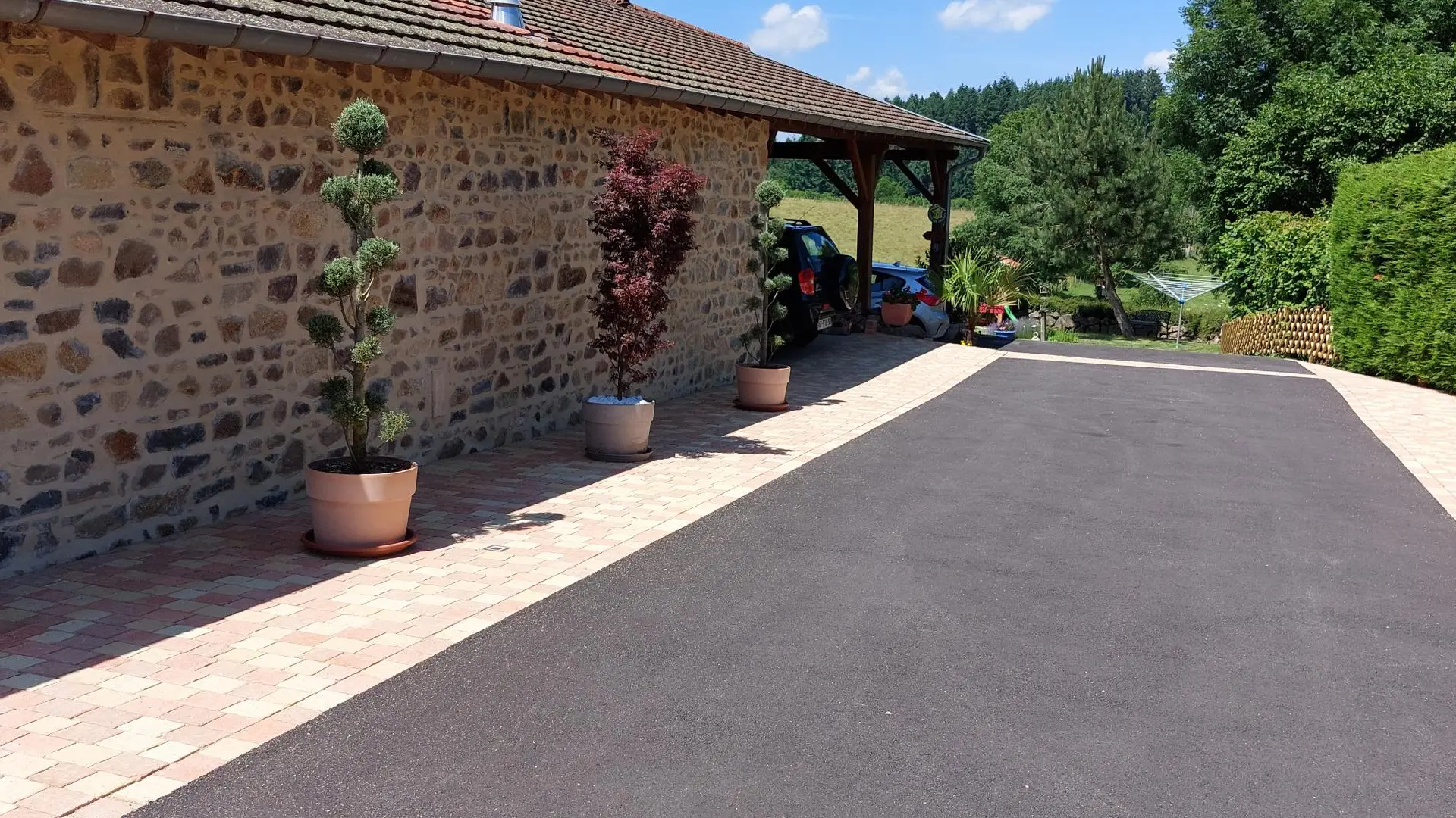 Entrée du parking avec abri couvert pour la voiture au fond juste devant le gîte