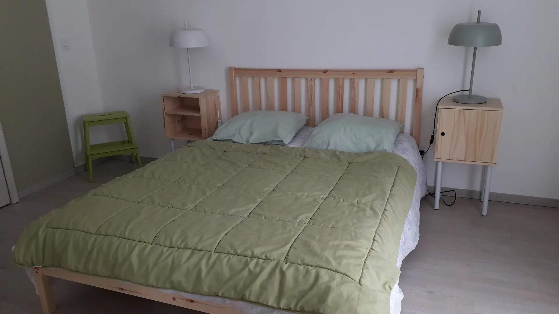 La chambre est meublée d'un lit double avec une tête de lit en bois, de deux tables de nuit et d'une lampe.