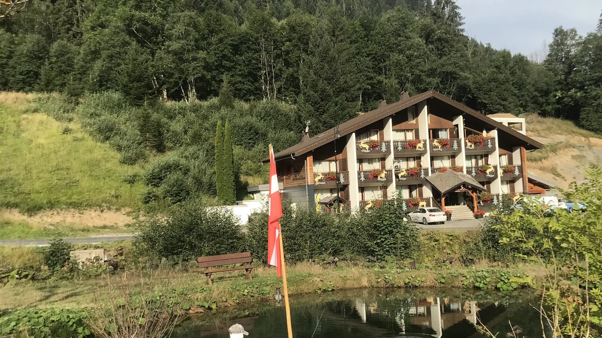 Vue de l'hôtel en été avec en premier plan petite barque avec un manequin sur un petit étang