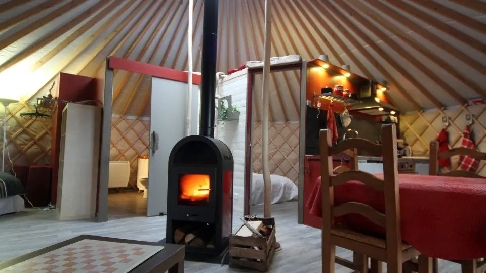 Yourte intérieure avec poêle à bois, kitchenette, table.