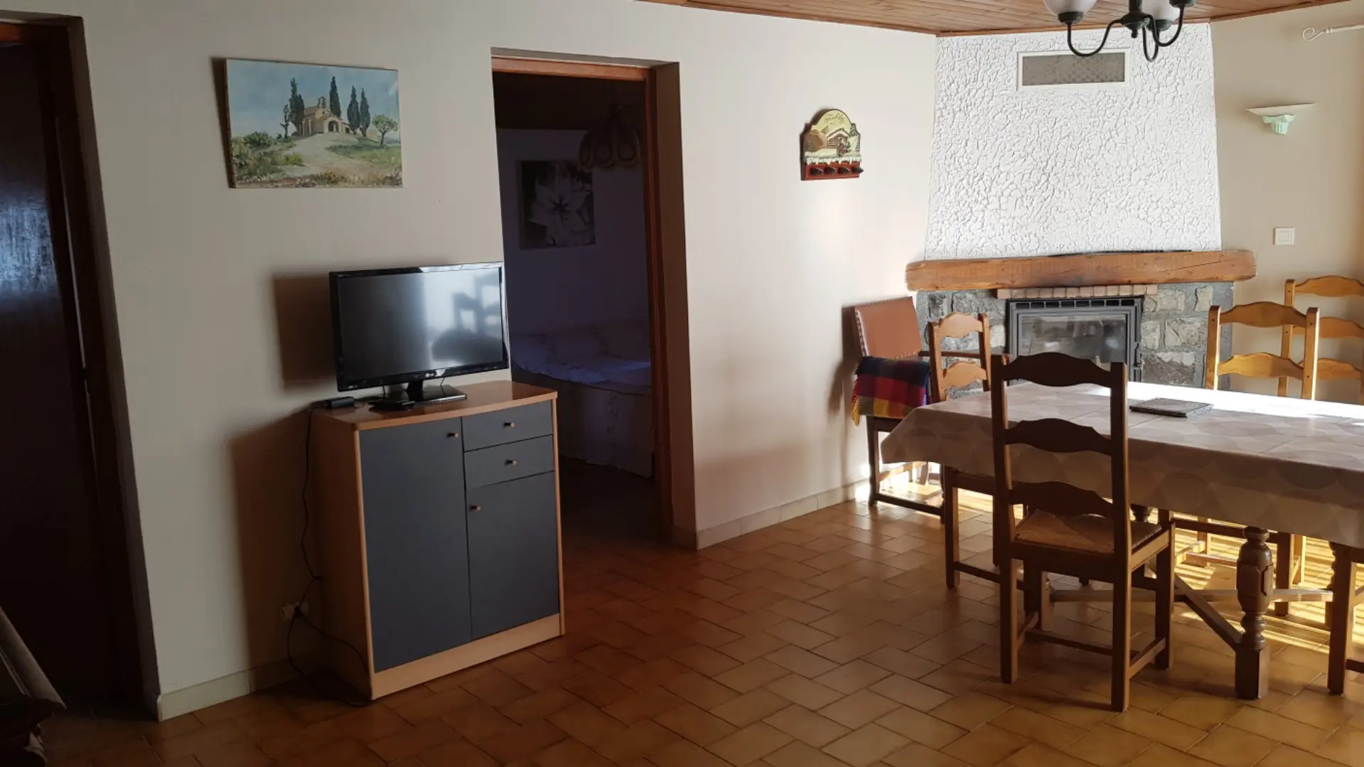 Séjour d'appartement avec TV, table à manger, cheminée, jonction vers chambre à coucher