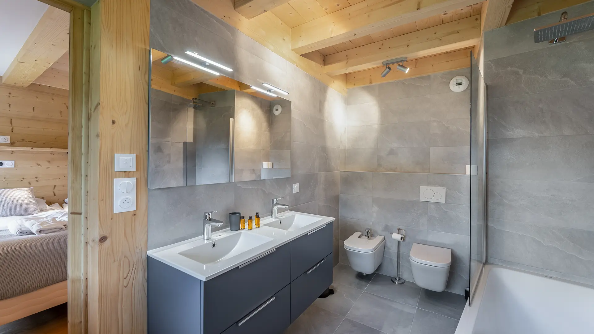 Salle de bains avec double vasque et son meuble, double miroir, deux toilettes et baignoire