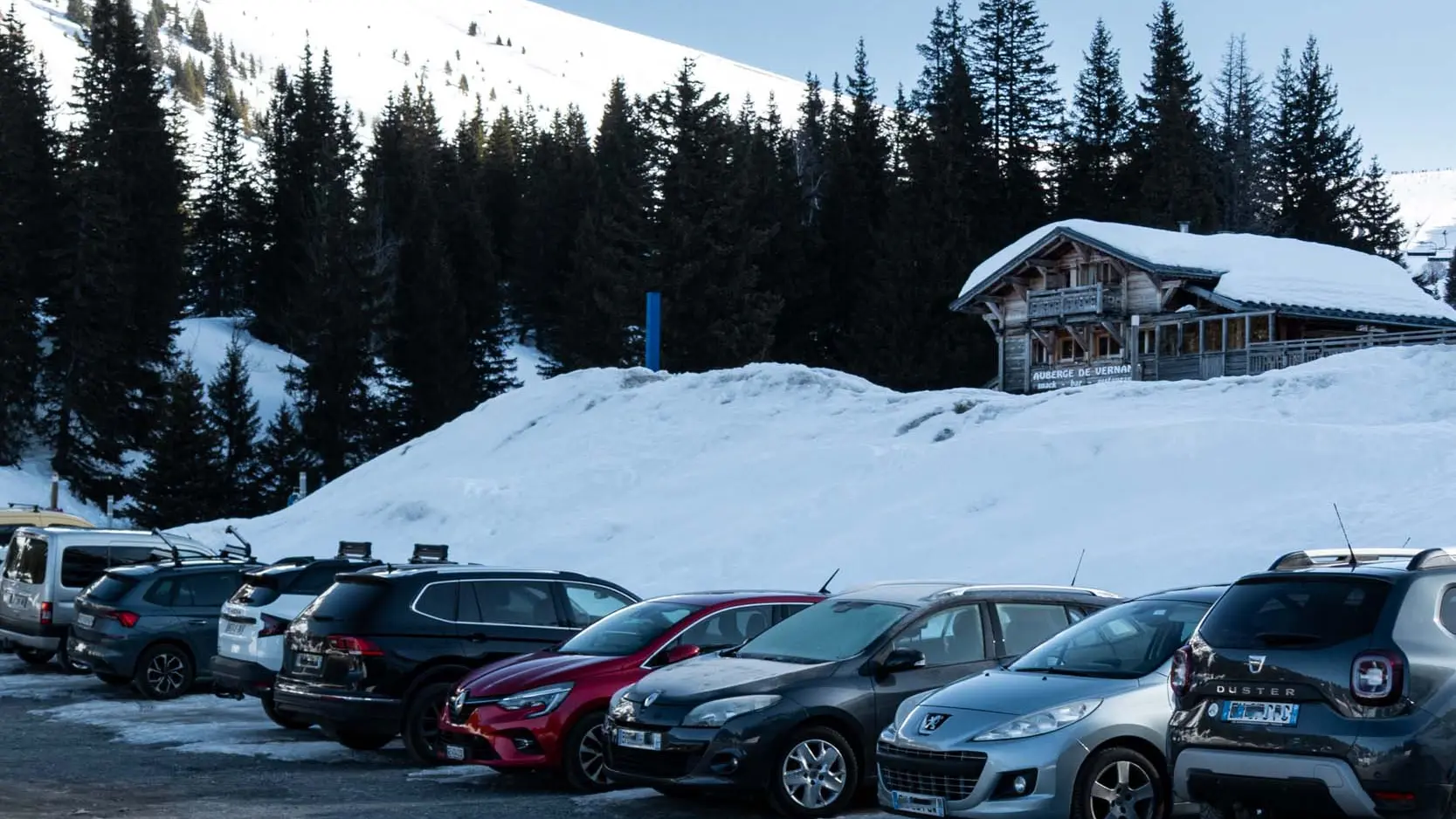 Auto's schuin geparkeerd op de parkeerplaats van Vernant, vlakbij de Auberge de Vernant.